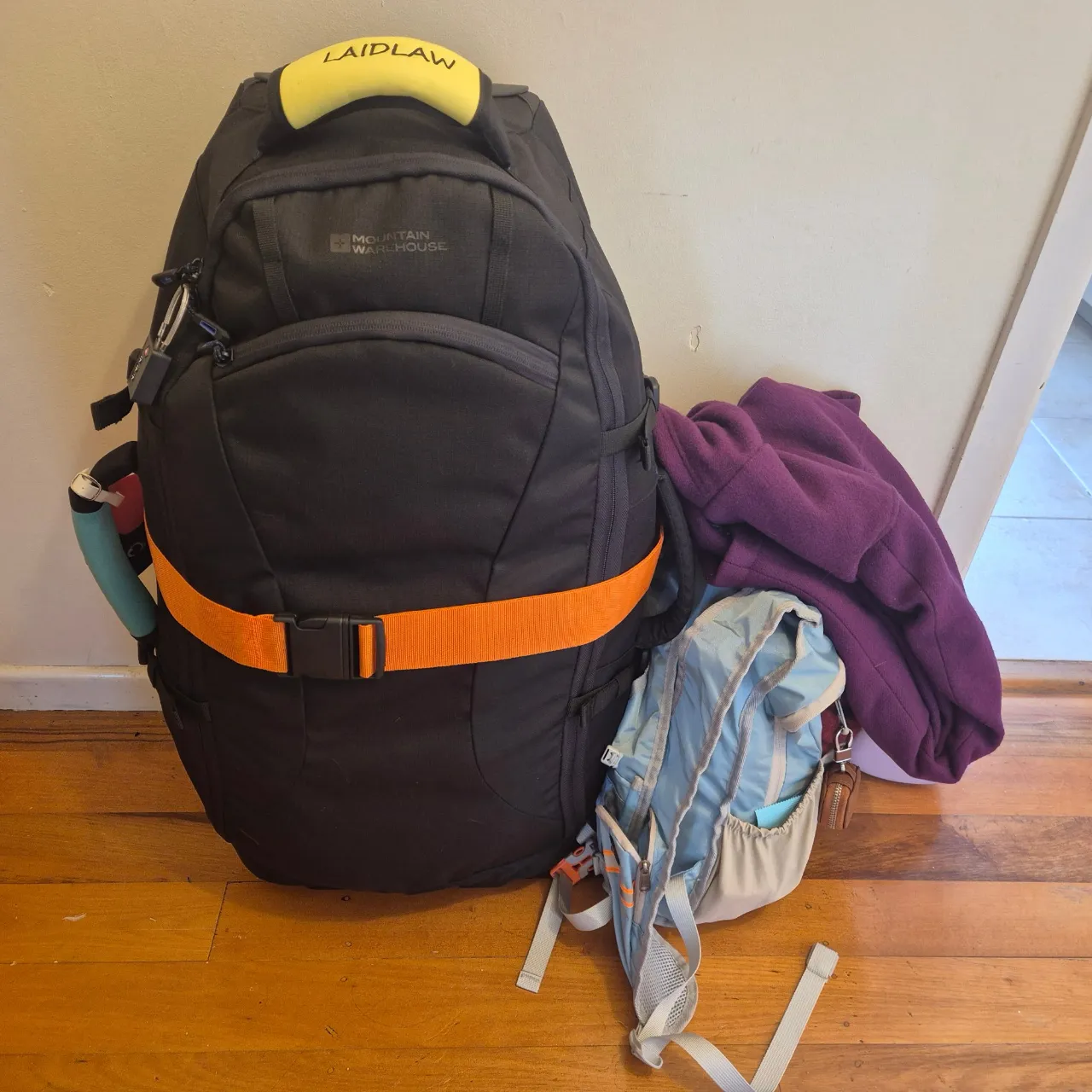 Two bags sitting on the floor - a larger black bag and a small blue backpack.