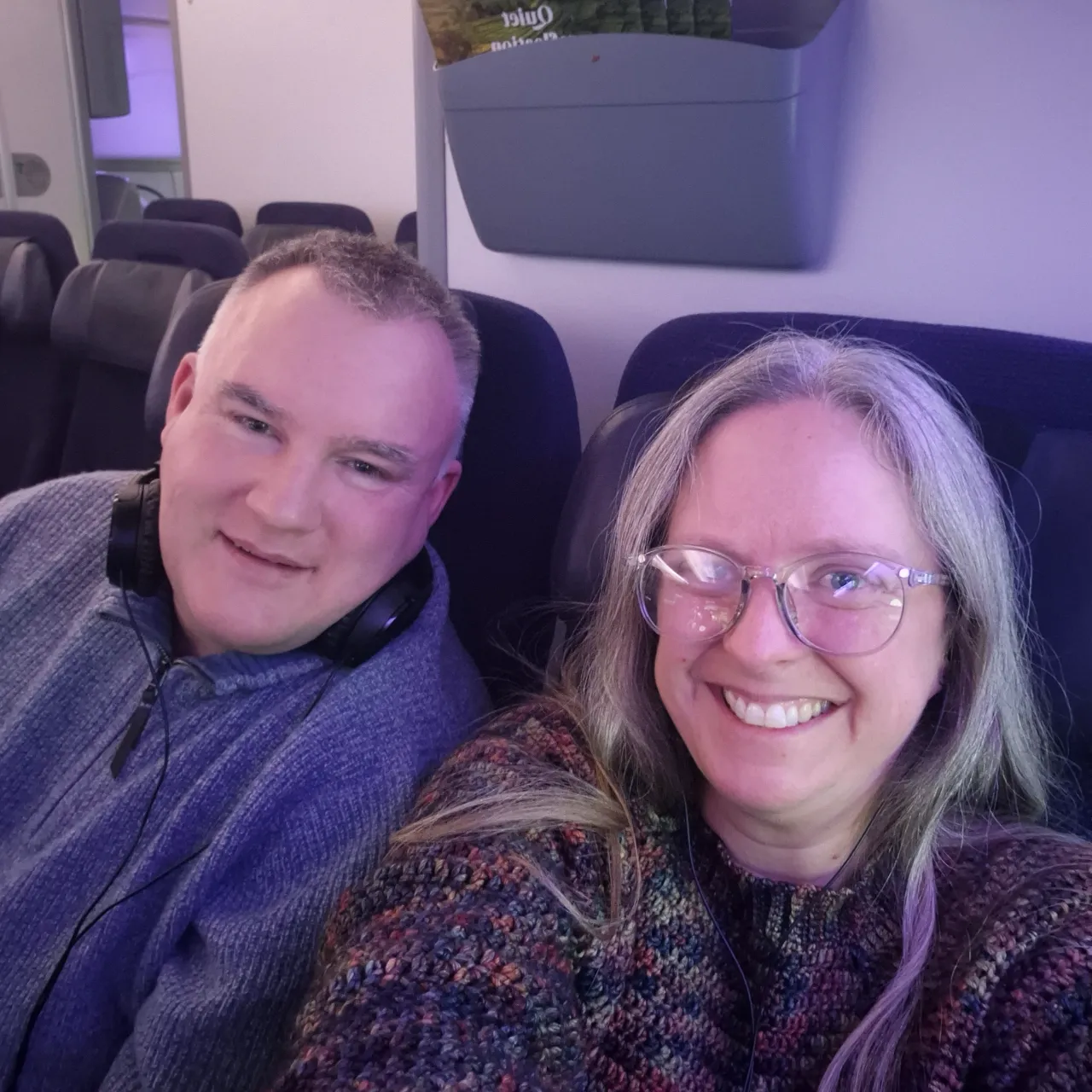 Duncan and Miriam smiling at the camera from their seats, a wall behind them.