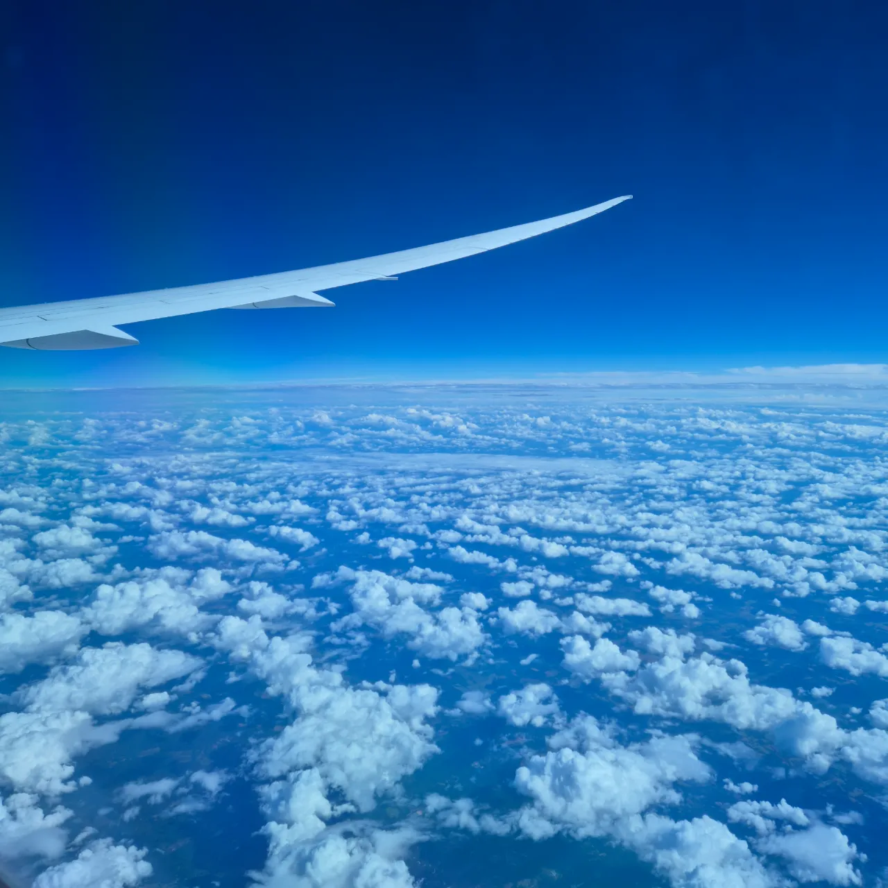 Blue sky looking down on clouds from an airplane.